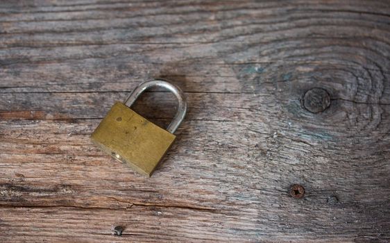Padlock is lying on rustic wooden desk, close up