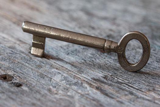 Old key is lying on a rustic wooden desk