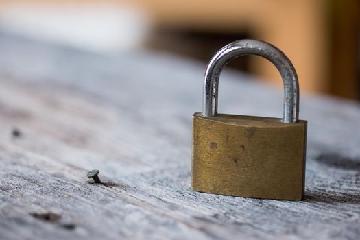 Padlock is lying on rustic wooden desk, close up