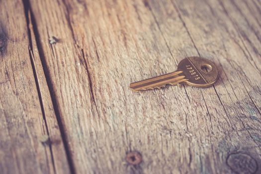 Old key is lying on a rustic wooden desk