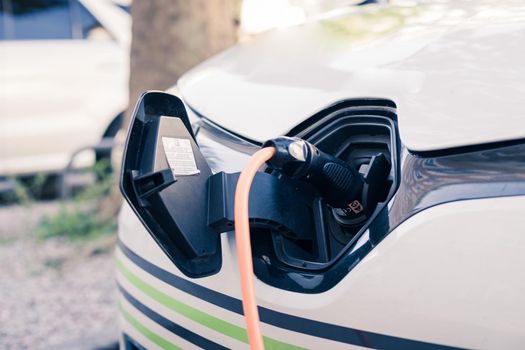 Electric car recharging with charge cable and plug leading to charge point.