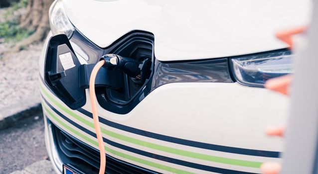 Electric car recharging with charge cable and plug leading to charge point.