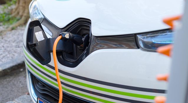Electric car recharging with charge cable and plug leading to charge point.