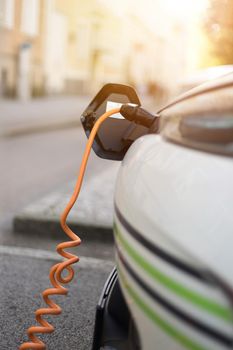 Electric car recharging with charge cable and plug leading to charge point.