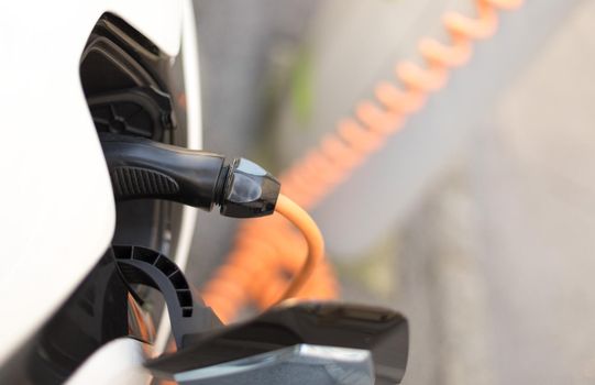 Electric car recharging with charge cable and plug leading to charge point.