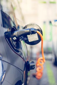 Electric car recharging with charge cable and plug leading to charge point.