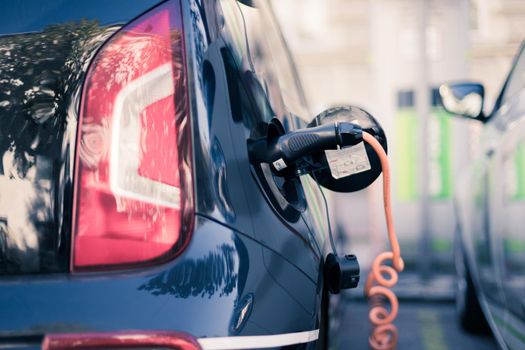 Electric car recharging with charge cable and plug leading to charge point.