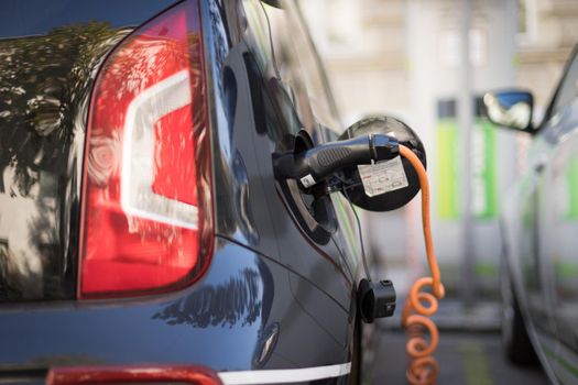 Electric car recharging with charge cable and plug leading to charge point.