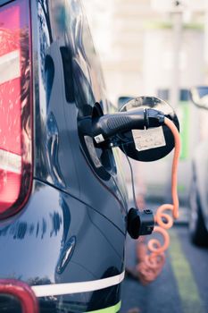 Electric car recharging with charge cable and plug leading to charge point.