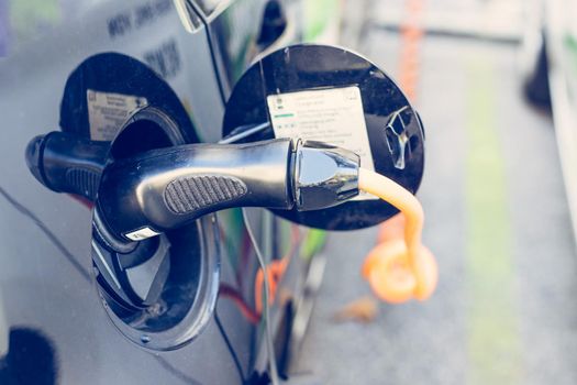 Electric car recharging with charge cable and plug leading to charge point.