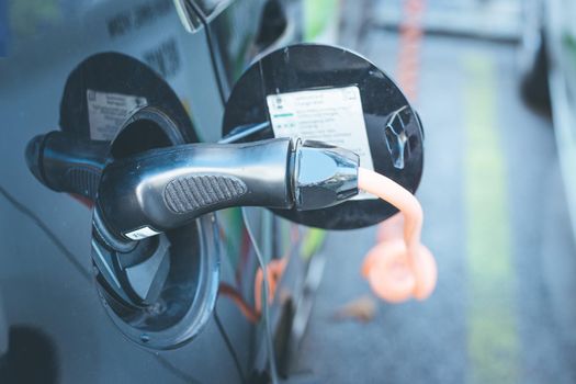 Electric car recharging with charge cable and plug leading to charge point.