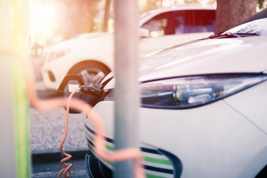 Electric car recharging with charge cable and plug leading to charge point.