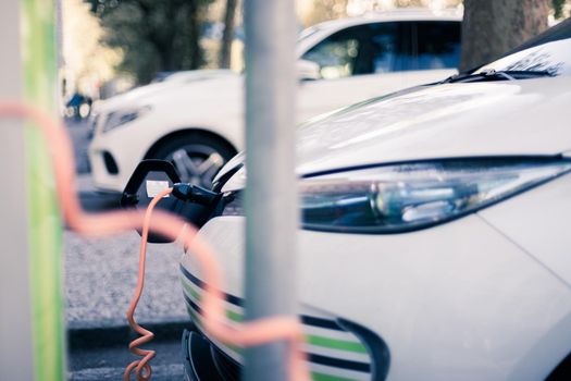 Electric car recharging with charge cable and plug leading to charge point.
