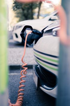 Electric car recharging with charge cable and plug leading to charge point.