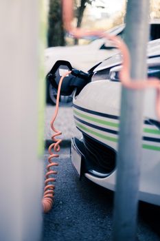 Electric car recharging with charge cable and plug leading to charge point.