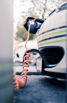 Electric car recharging with charge cable and plug leading to charge point.