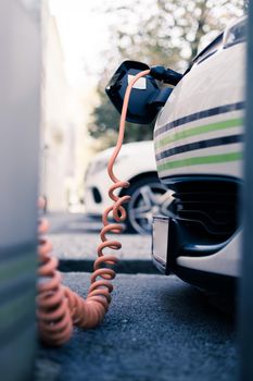 Electric car recharging with charge cable and plug leading to charge point.