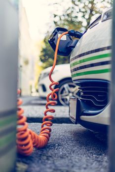 Electric car recharging with charge cable and plug leading to charge point.