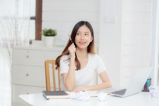 Young asian woman confident working at home with laptop computer and thinking idea for planning, freelance happy girl excited and success using notebook thoughtful and writing, business concept.