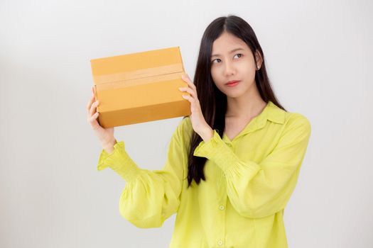 Young asian woman smiling and holding cardboard box with surprise at home, happy female carrying parcel box with excited, present and gift, packaging for deliver, online shopping store and service concept.