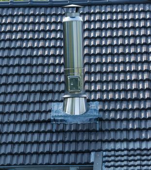 A roofed stainless steel chimney in the background roof tiles. Copy space for text.
