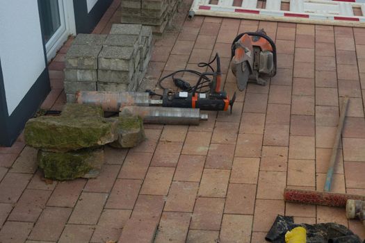 Concrete drilling with industrial boring machine next to it is a stone cutting saw