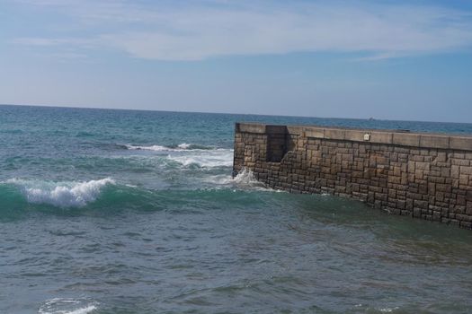 High waves at a breakwater on Cran Canaria in Meloneras, beach near lighthouse.