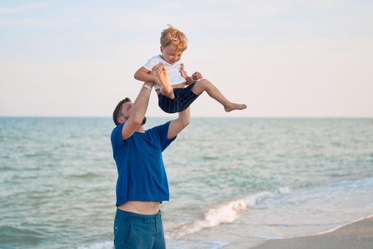 Father throwing son spending time together sea vacation Young dad child little boy walking beach Fathers day. Family with one child. Happy childhood with daddy.