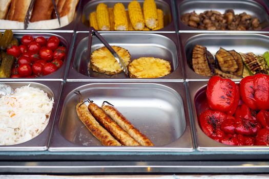 Street food grilled tomato, sausages, pineapple, sauerkraut, pepper, vegetable, corn, showcase market in metal plate