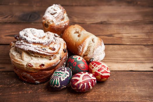 Traditional easter cake Kraffin stands on wooden table against a dark background. Spring holiday bread with copy space Painted easter eggs