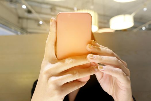 Close up of women's hands with a pink nails holding cell telephone, hipster girl watching video and texting a message to her family on mobile phone during coffee break in restaurants