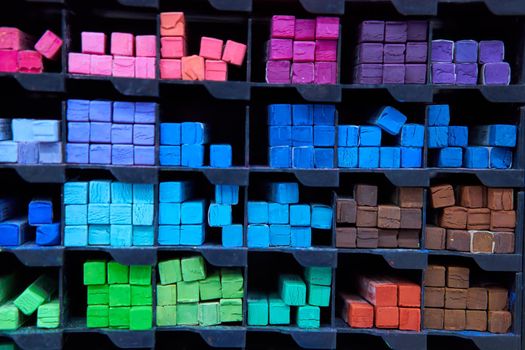 Multicolored pastel crayons art store in wooden cells. Artspace, workshop, creativity concept. Modern art. Style abstract background