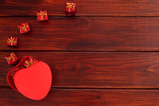 Heart shaped red box for valentines day gift on dark wooden table, top view