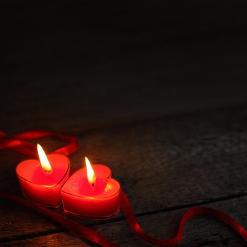 Heart shaped candles burning on wooden background, Valentines day concept
