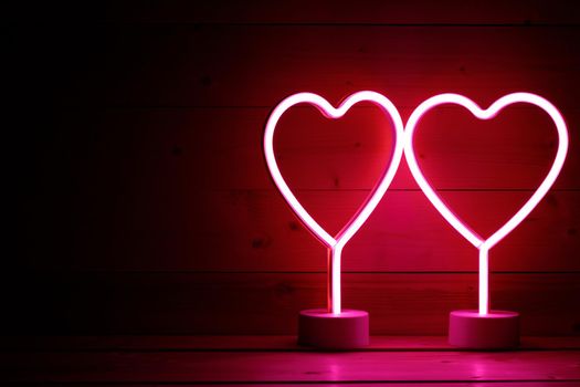 Two glowing pink neon hearts Valentines day party concept