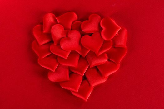 Valentine's day many red silk hearts on red background, love concept