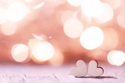 Two handmade wooden hearts on beautiful pink bokeh background. Vintage style. Love Valentine's Day concept.