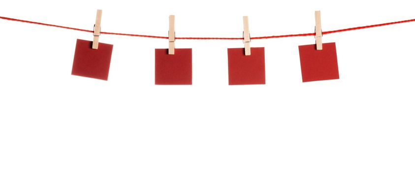 Set of four red blank paper notes held on a string with clothespins isolated on white background