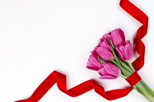 Valentines day pink tulip flowers and red ribbon isolated on white background