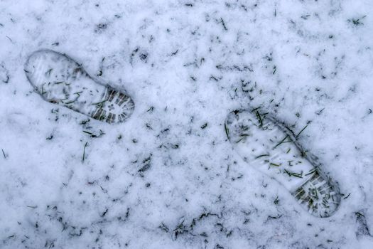 Footsteps of male shoes in fresh white snow in winter.