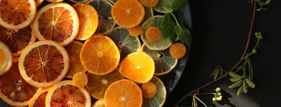 Citrus fruits orange, lemon, mandarin, lime. Summer autumn background on black marble table. Harvest concept. Horizontal flat lay