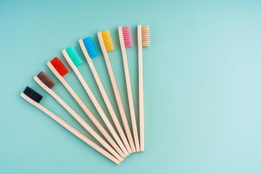 A set of Eco-friendly antibacterial toothbrushes made of bamboo wood on a light green background. Environmental care trends.