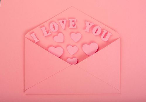 Pink love letter and wooden hearts painted I love you letters on pink background
