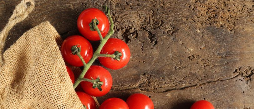 Rustic background with tomatoes, canvas bag on old wood.