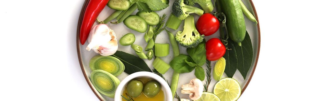 Fresh vegetables over white. Tomato, olive, cucumber, garlic on plate. Horizontal flat lay