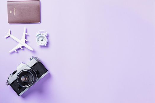Top view flat lay mockup of retro camera films, airplane, passport travel accessories isolated on a purple background with copy space, Business trip, and vacation summer travel concept