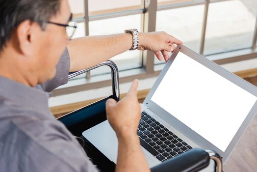 Asian senior disabled businessman in a wheelchair with laptop computer discuss together with team in office. Old father man sitting wheelchair and his son talking video calls conference on laptop