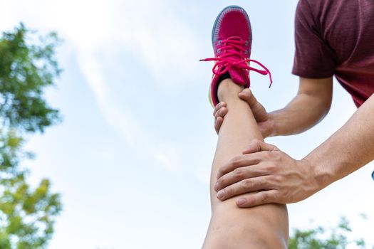 Male hand grab female leg to stretch after exercise injury.