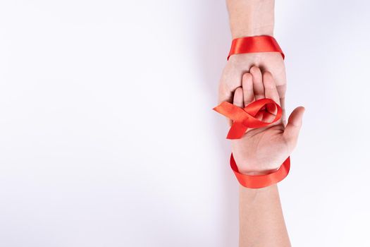 Aids awareness, man and woman hands holding red ribbon on white background with copy space for text. World Aids Day, Healthcare and medical concept.