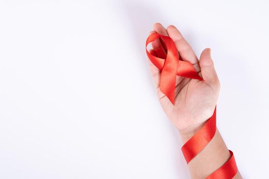 Aids awareness, woman hands holding red ribbon on white background with copy space for text. World Aids Day, Healthcare and medical concept.